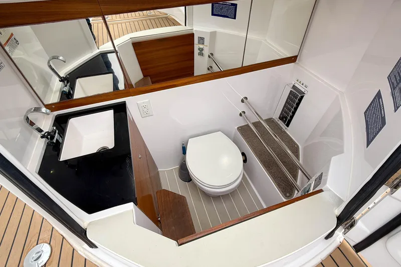 Slide: The Image of 2020 Axopar 28 Cabin bathroom with sink, toilet, and wooden accents. - 21