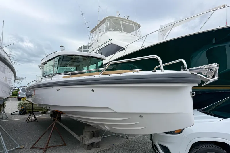 Slide: The Image of 2020 Axopar 28 Cabin with Wet Bar, displayed on stands in a marina. - 22