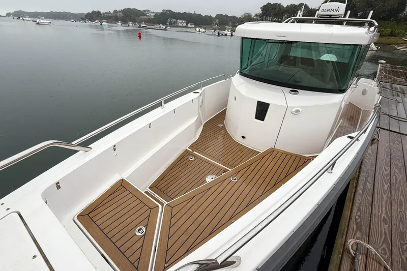 Slide: The Image of 2020 Axopar 28 Cabin with Wet Bar, docked, featuring sleek design and wooden deck. - 24