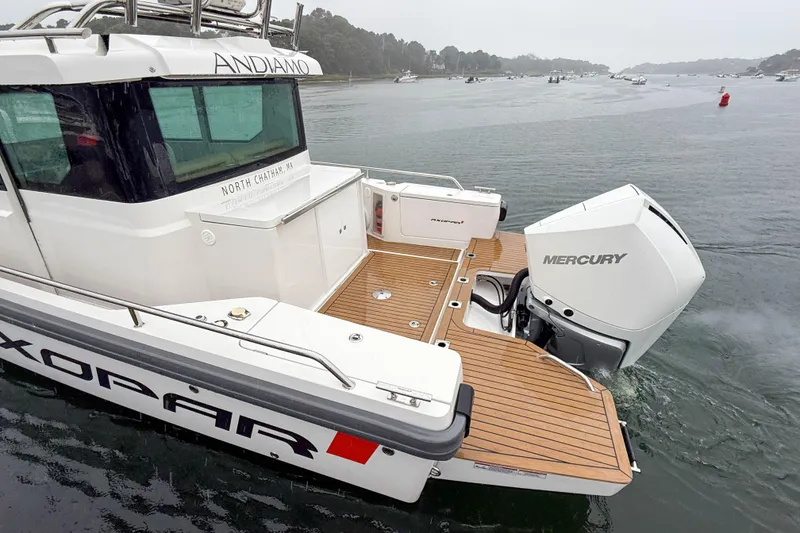 Slide: The Image of 2020 Axopar 28 Cabin with Wet Bar, featuring Mercury engine, on a calm waterway. - 3