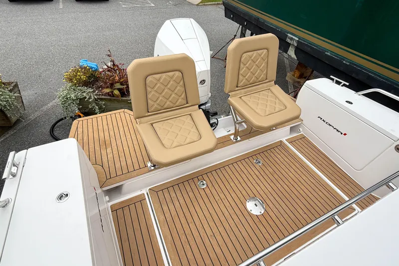 Slide: The Image of 2020 Axopar 28 Cabin with Wet Bar, featuring tan seats and teak flooring. - 8