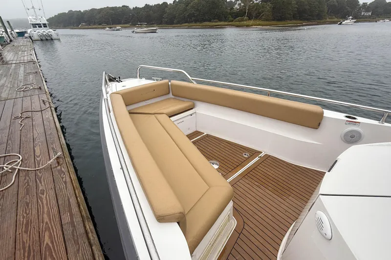 Slide: The Image of 2020 Axopar 28 Cabin with Wet Bar, docked, featuring tan seating and wooden deck. - 9