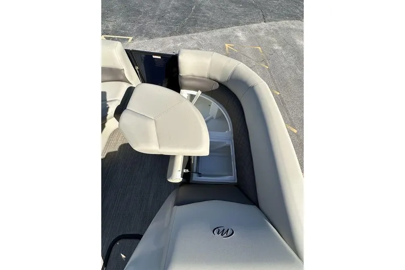 Slide: The Image of 2026 Manitou 23 Encore RF boat interior with beige seating and storage compartment. - 19