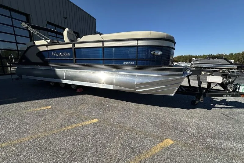 Slide: The Image of 2026 Manitou 23 Encore RF pontoon boat on trailer, parked outdoors. - 4