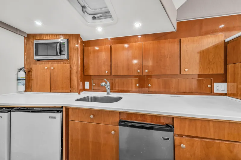 Slide: The Image of 1978 Hatteras 42 Convertible yacht kitchen with wooden cabinets, microwave, and sink. - 18