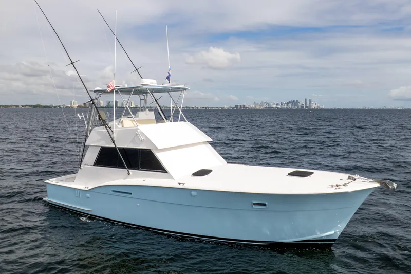 Slide: The Image of 1978 Hatteras 42 Convertible yacht on open water with city skyline in background. - 2