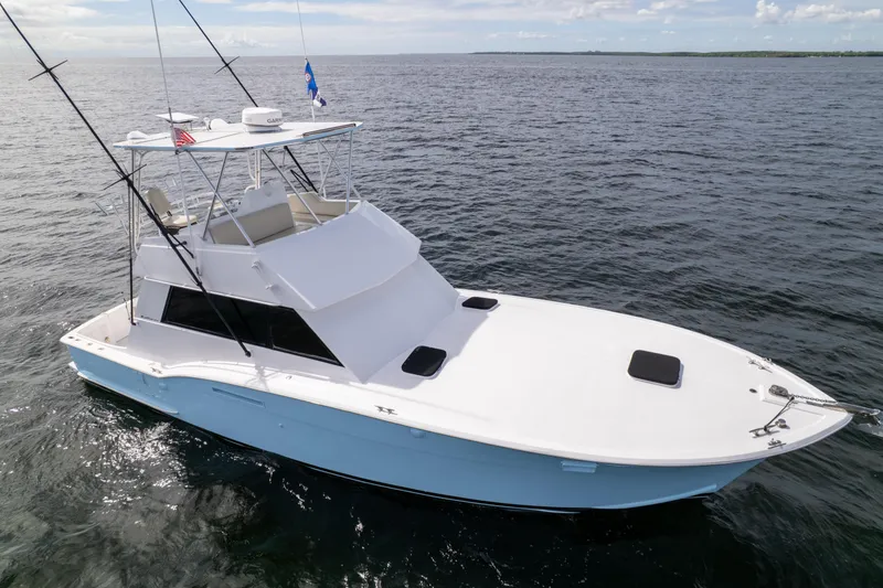 Slide: The Image of 1978 Hatteras 42 Convertible yacht on open water, showcasing sleek design and fishing equipment. - 4