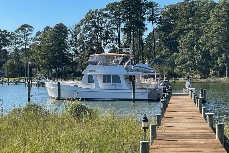Slide: The Image of 2011 Grand Banks 47 Heritage EU yacht docked by a wooden pier, surrounded by trees. - 6