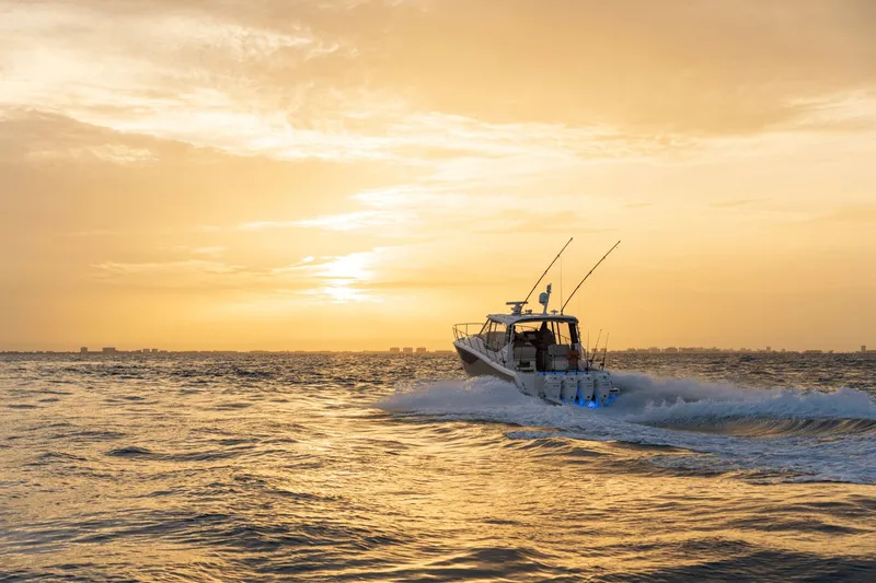 Slide: The Image of A Boston Whaler 405 Conquest cruises on the sea at sunset, with fishing rods on board. - 10