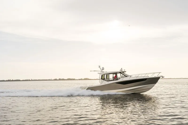 Slide: The Image of A 2027 Boston Whaler 405 Conquest speeds across calm water at sunset. - 17
