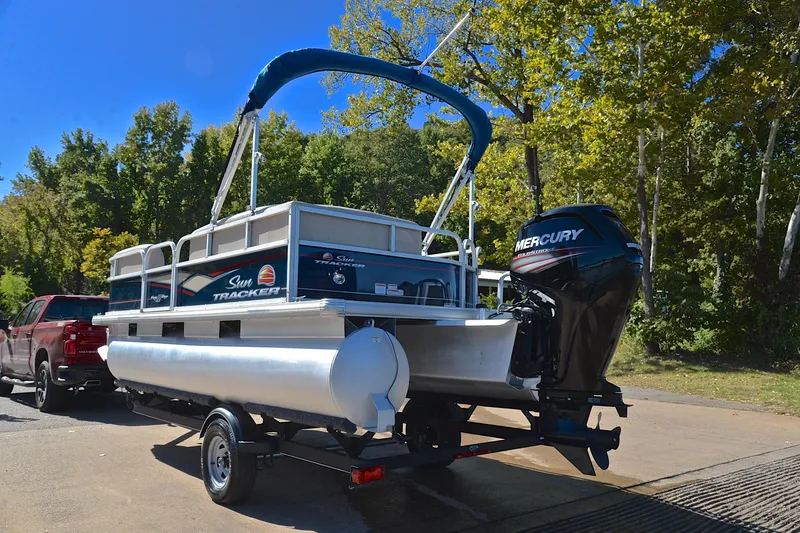 Slide: The Image of 2019 Sun Tracker Party Barge 18 DLX on trailer, parked near trees. - 12