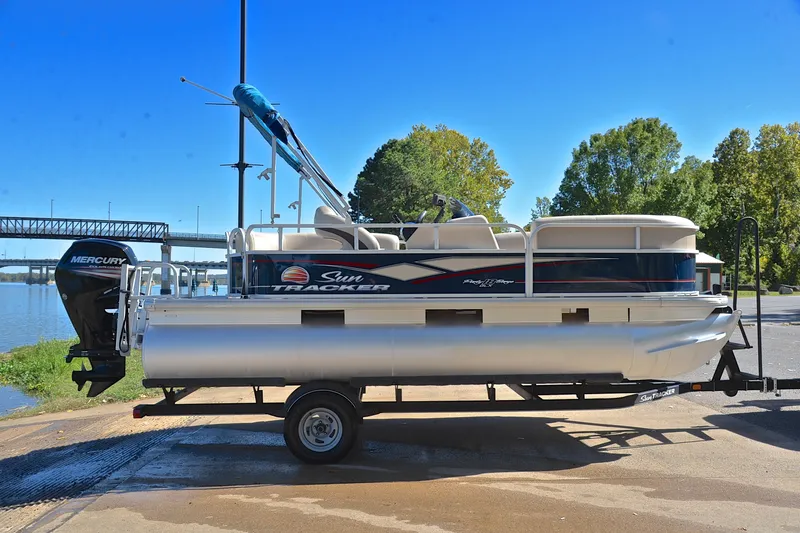 Slide: The Image of 2019 Sun Tracker Party Barge 18 DLX pontoon boat on trailer by a river. - 15