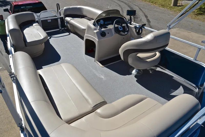 Slide: The Image of 2019 Sun Tracker Party Barge 18 DLX interior with beige seating and steering console. - 24