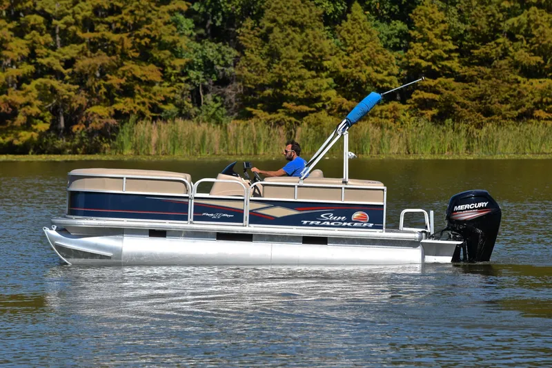 Slide: The Image of 2019 Sun Tracker Party Barge 18 DLX pontoon boat cruising on a serene lake. - 9