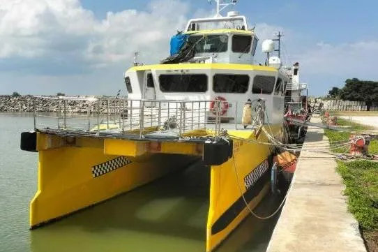 Slide: The Image of Yellow Offshore Fast Crew Taxi Catamaran by Mützelfeldtwerft, 2016, docked at a pier. - 5