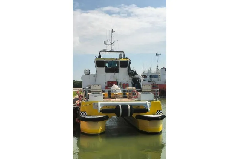 Slide: The Image of Yellow Offshore Fast Crew Taxi Catamaran by Mützelfeldtwerft, 2016, docked in calm waters. - 6