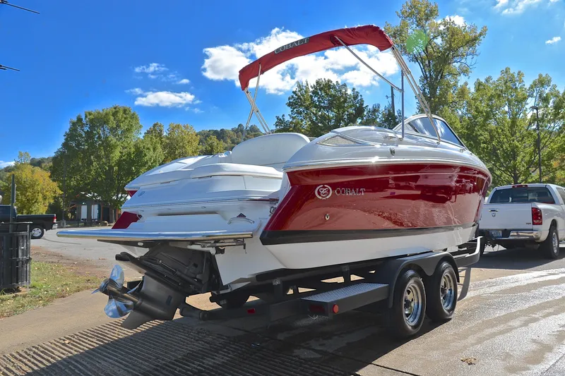 Slide: The Image of 2007 Cobalt 232 boat on trailer, red and white, sunny day, trees in background. - 11