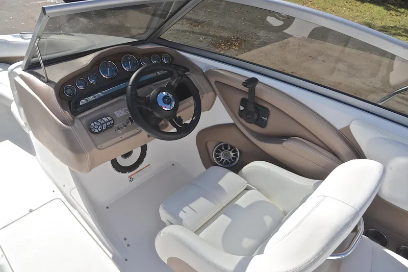 Slide: The Image of 2007 Cobalt 232 boat interior with steering wheel, dashboard, and white seating. - 22