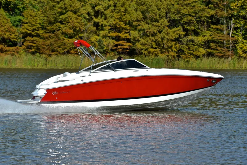 Slide: The Image of 2007 Cobalt 232 boat cruising on a lake with lush green trees in the background. - 3