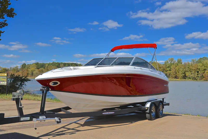 Slide: The Image of 2007 Cobalt 232 boat with red hull on trailer by a lake under blue sky. - 7