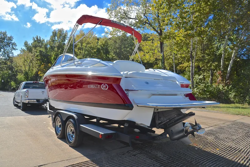 Slide: The Image of 2007 Cobalt 232 boat on trailer, parked near trees under a clear blue sky. - 9