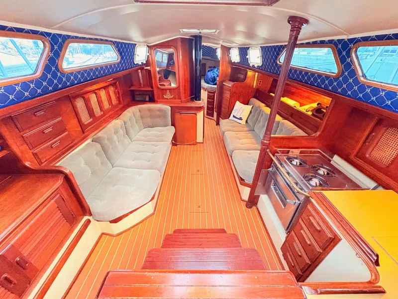 Slide: The Image of 1978 Islander 36 yacht interior with wood finish, cushioned seating, and compact kitchen area. - 10