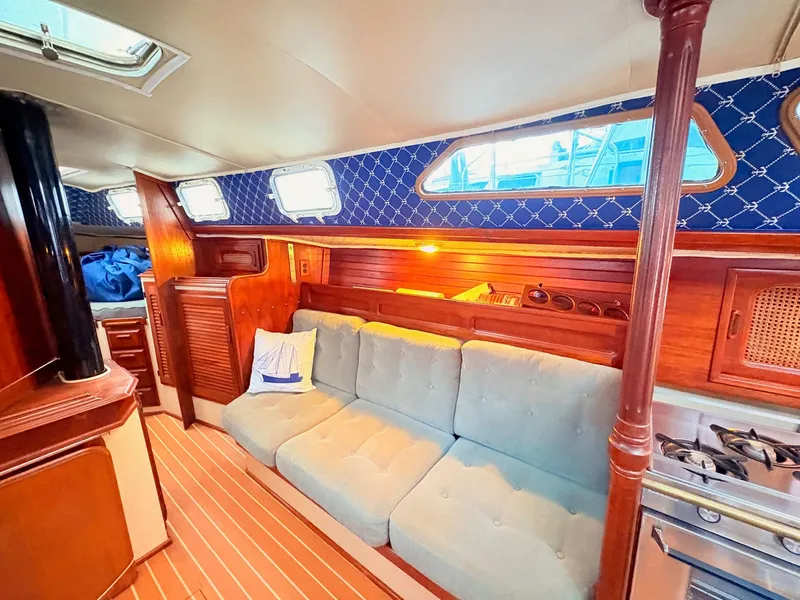 Slide: The Image of 1978 Islander 36 yacht interior with cozy seating, wooden cabinetry, and nautical decor. - 12