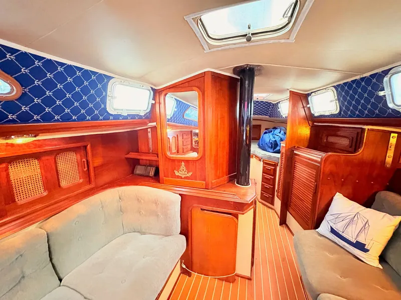 Slide: The Image of 1978 Islander 36 yacht interior with wooden finish, blue accents, and cozy seating area. - 13
