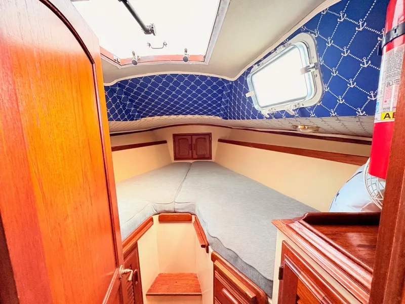 Slide: The Image of 1978 Islander 36 sailboat cabin with cozy bed, wooden accents, and nautical decor. - 15