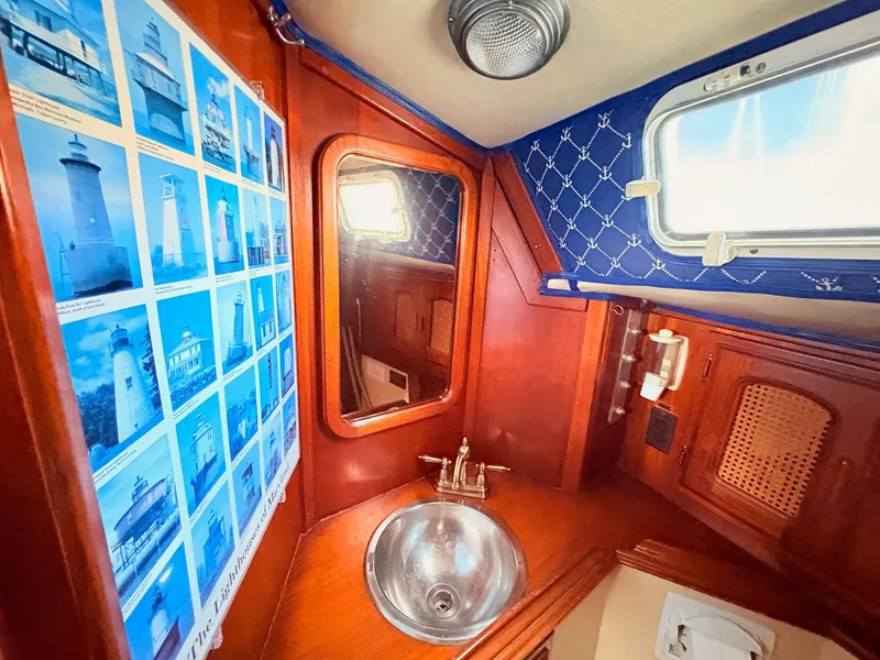 Slide: The Image of 1978 Islander 36 yacht bathroom with lighthouse photos, wooden cabinetry, and nautical decor. - 19