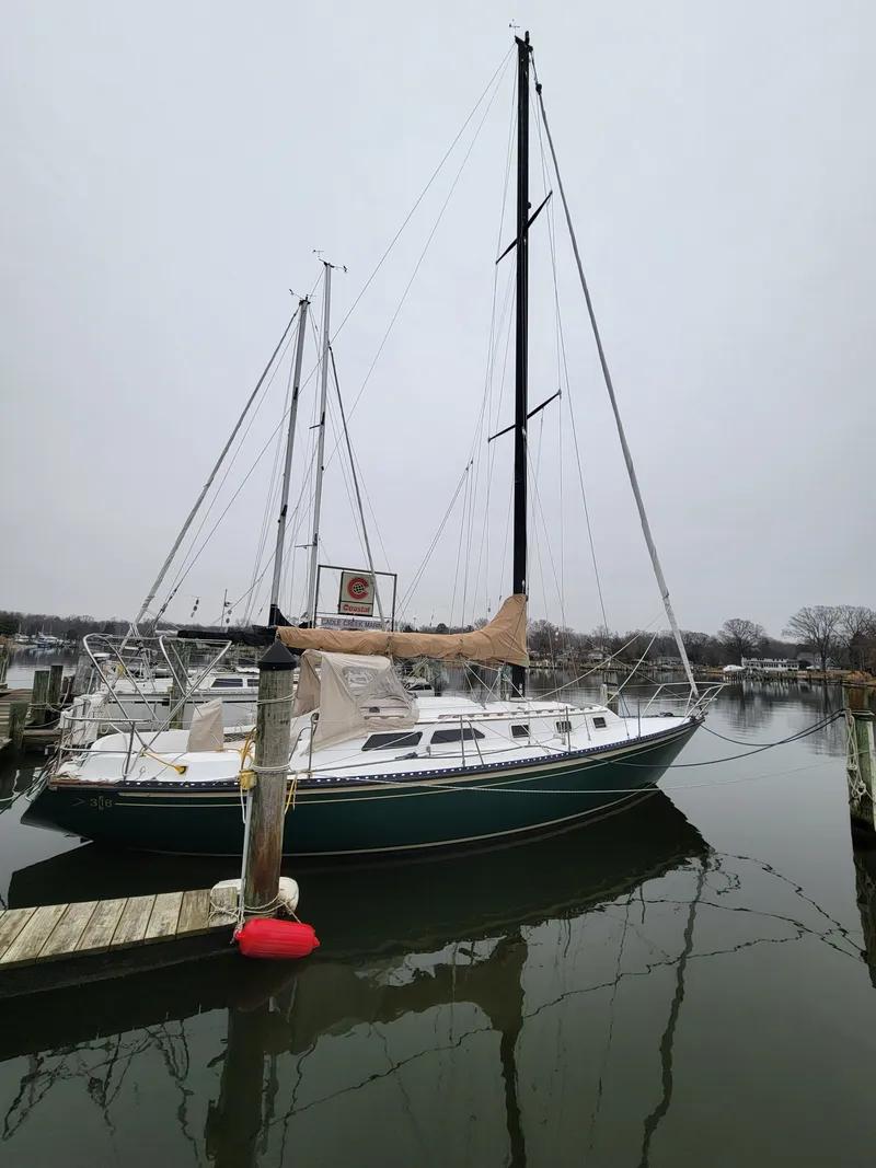 Slide: The Image of 1978 Islander 36 sailboat docked in a calm marina on a cloudy day. - 2