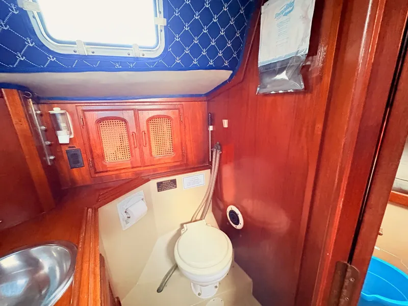 Slide: The Image of 1978 Islander 36 yacht bathroom with wooden cabinets, sink, and toilet. - 20