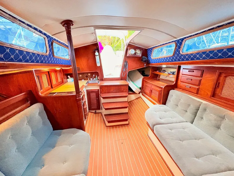 Slide: The Image of 1978 Islander 36 sailboat interior with wood finish, blue accents, and cozy seating. - 21