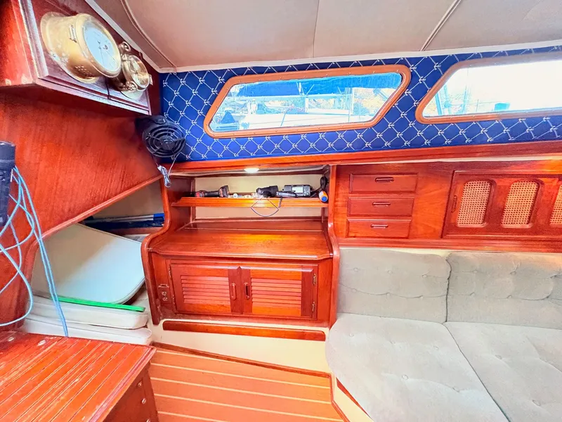 Slide: The Image of 1978 Islander 36 yacht interior with wooden cabinetry, blue accents, and cozy seating area. - 22