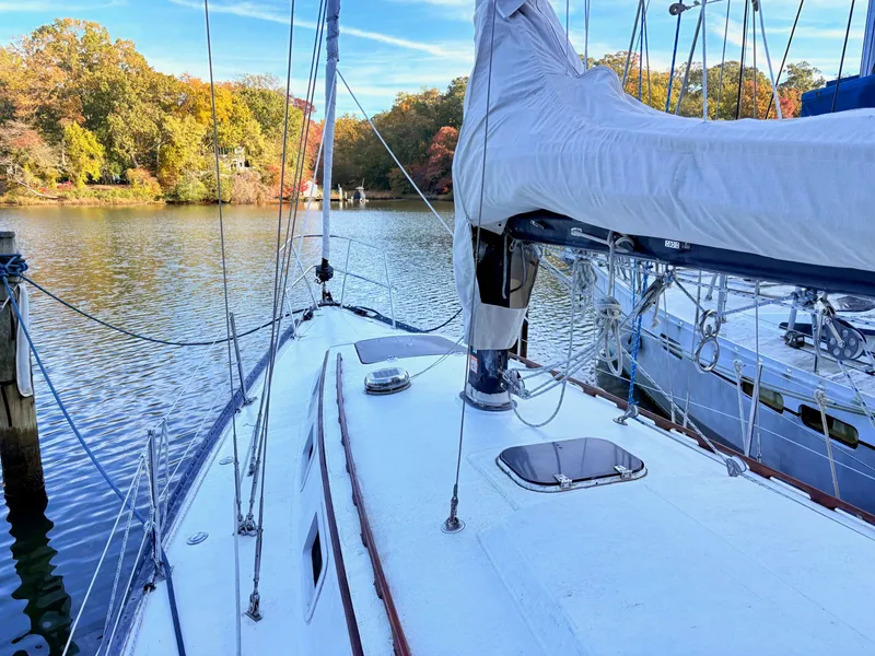 Slide: The Image of 1978 Islander 36 sailboat docked on a serene lake with autumn foliage. - 25