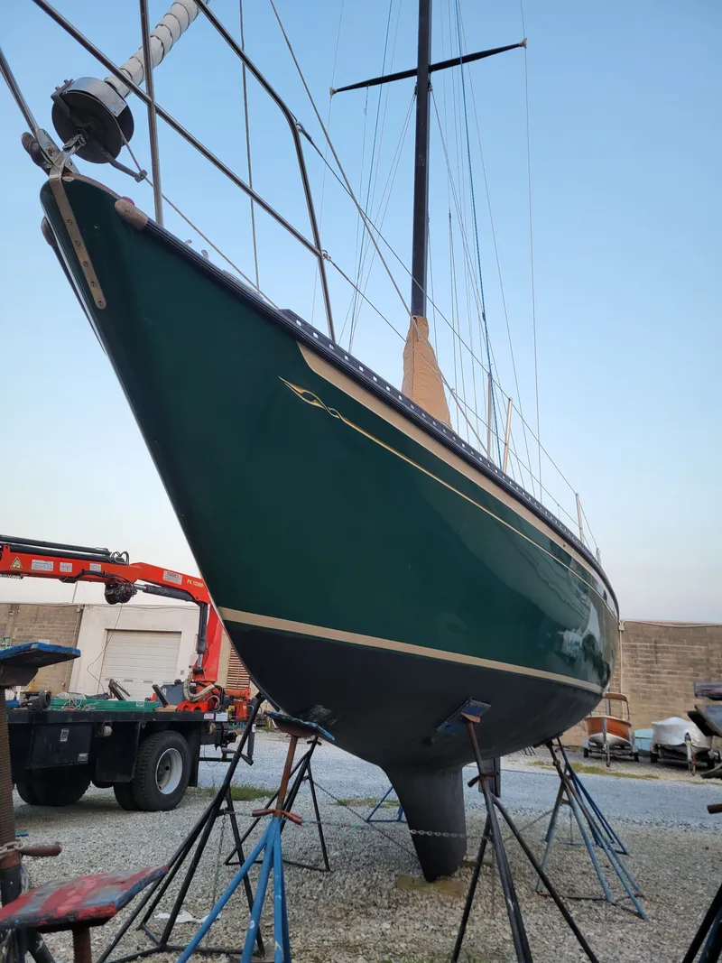 Slide: The Image of 1978 Islander 36 sailboat on stands, green hull, in a boatyard setting. - 6