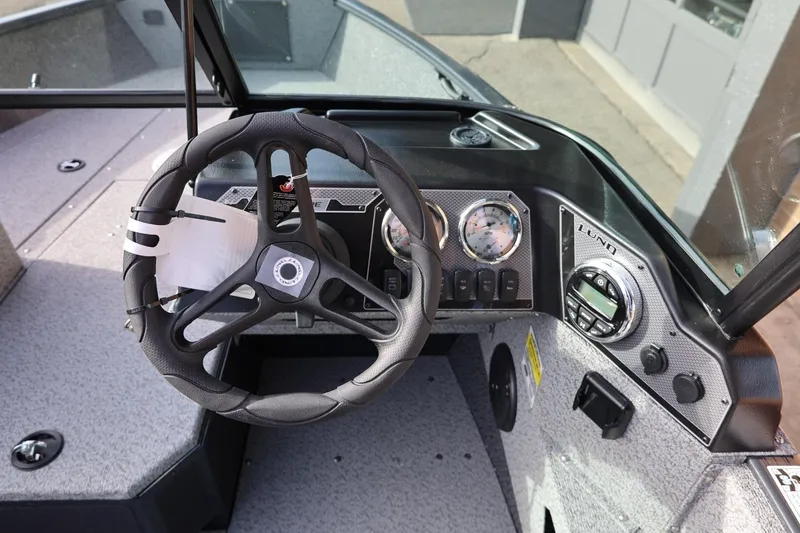 Slide: The Image of 2026 Lund 1675 Adventure Sport boat dashboard with steering wheel and gauges. - 19