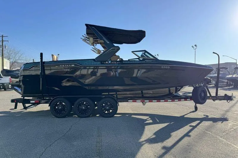 Slide: The Image of 2026 MasterCraft XStar 25 boat on a trailer in a parking lot. - 22