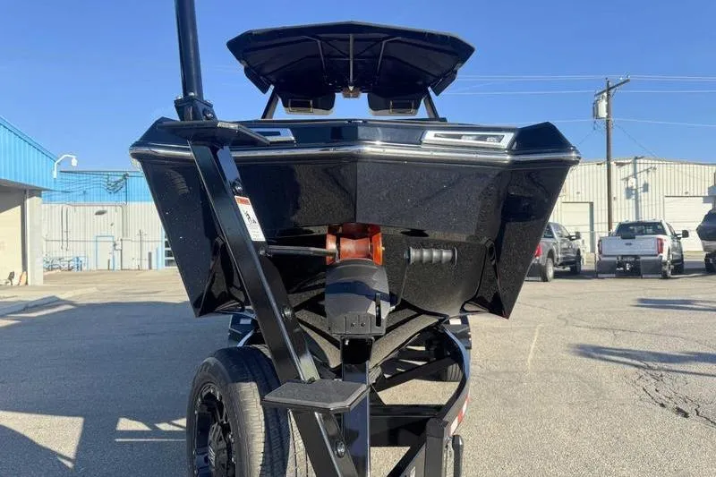 Slide: The Image of 2026 MasterCraft XStar 25 boat on trailer, parked outdoors under clear blue sky. - 24