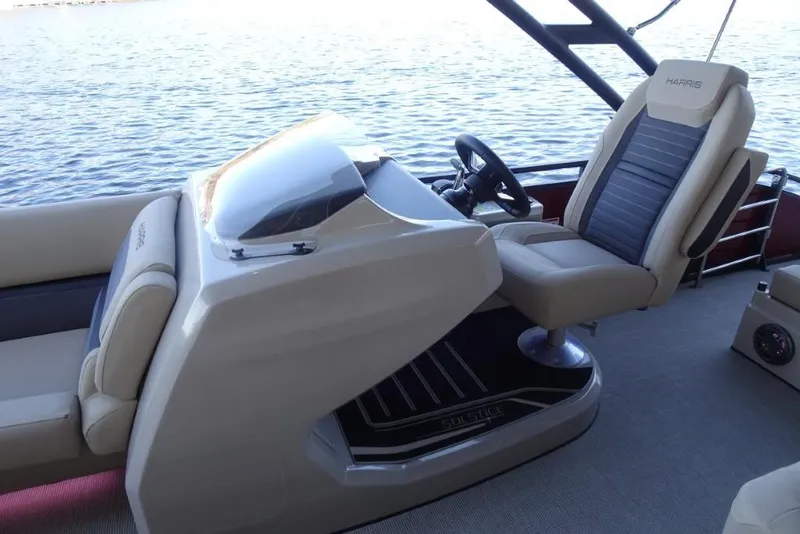 Slide: The Image of 2026 Harris Solstice 250 boat interior with captain's chair and steering wheel on a calm lake. - 19