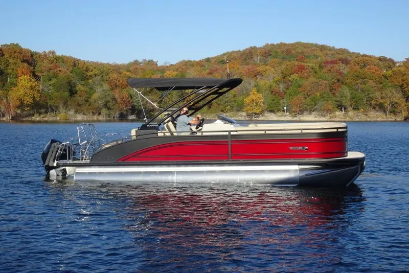 Slide: The Image of 2026 Harris Solstice 250 pontoon boat on a scenic lake with autumn foliage. - 2