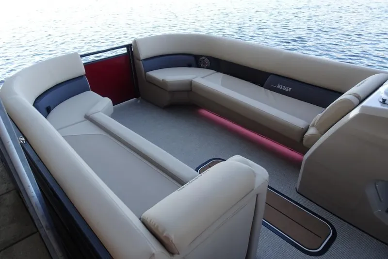 Slide: The Image of 2026 Harris Solstice 250 pontoon boat interior with beige seating, on calm water. - 21