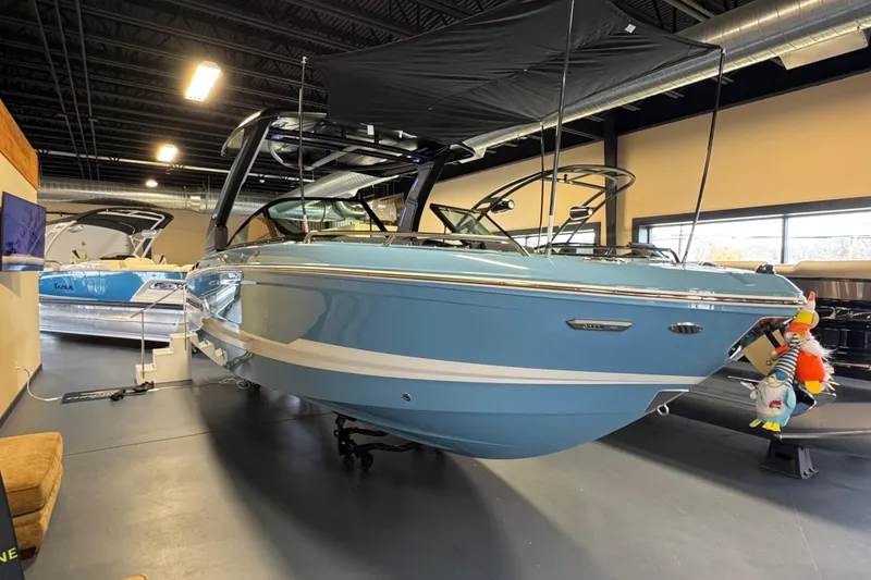 The Image of 2026 Chaparral 267 SSX boat in showroom, blue exterior, black canopy, modern design. - 0