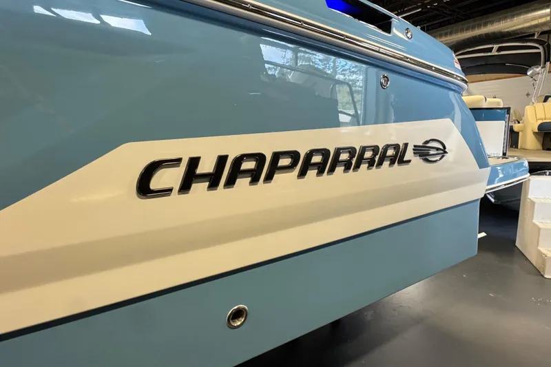 Slide: The Image of 2026 Chaparral 267 SSX boat, blue and white exterior, showroom display. - 2