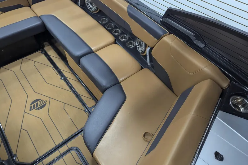 Slide: The Image of 2022 Malibu Wakesetter 22 LSV interior with tan and black seating, cup holders, and logo flooring. - 17