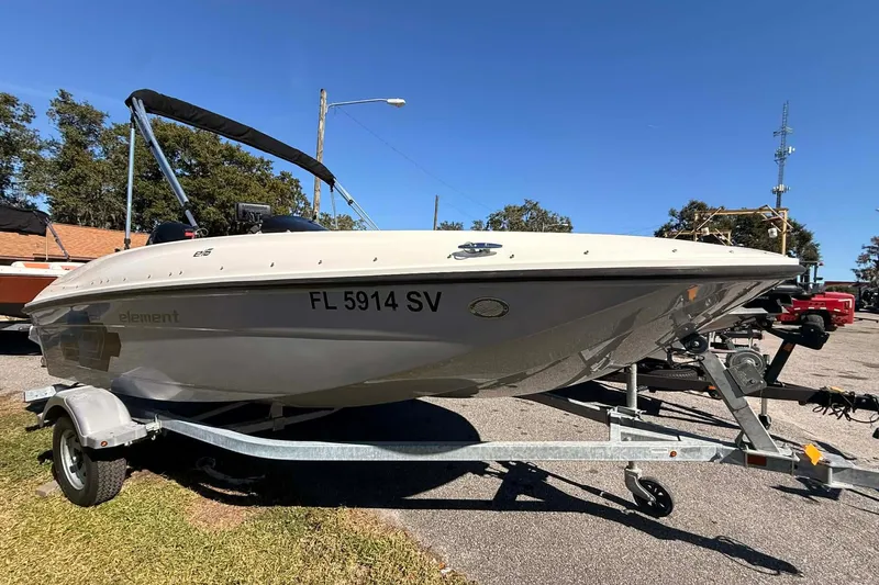 Slide: The Image of 2021 Bayliner Element E16 boat on trailer, parked outdoors under clear blue sky. - 1