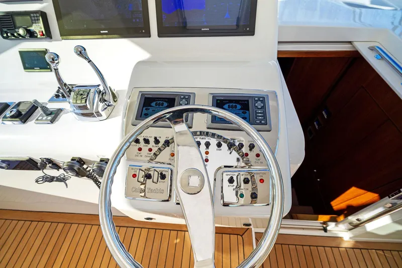 Slide: The Image of Control panel of a 2012 Cabo 44 Hardtop Express boat with steering wheel and navigation instruments. - 37