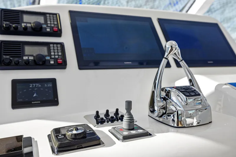 Slide: The Image of Control panel of a 2012 Cabo 44 Hardtop Express yacht with navigation screens and throttle. - 42