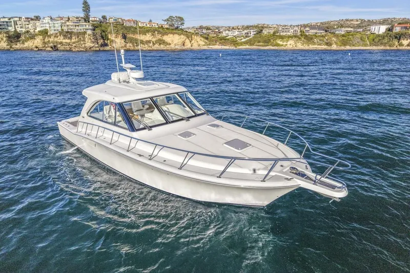 Slide: The Image of 2012 Cabo 44 Hardtop Express yacht cruising near scenic coastline. - 83