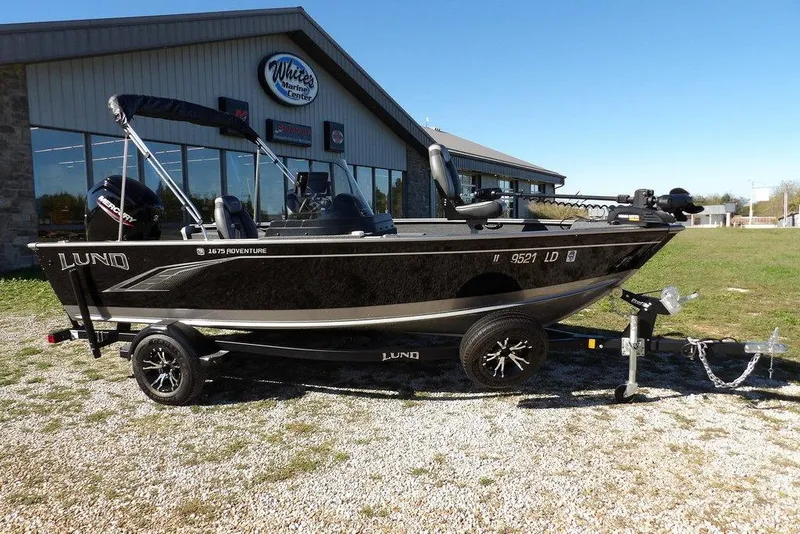 The Image of 2023 Lund 1675 Adventure SS boat on trailer outside marine center. - 1
